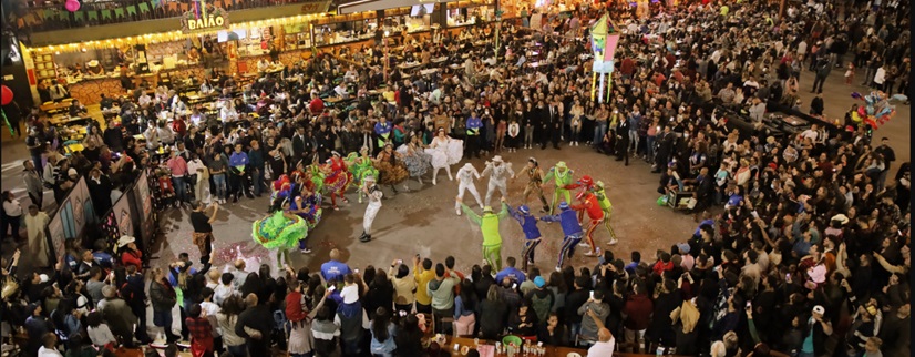 imagem de uma apresentação de quadrilha em umclaarão no meio de uma multidão na festa junina