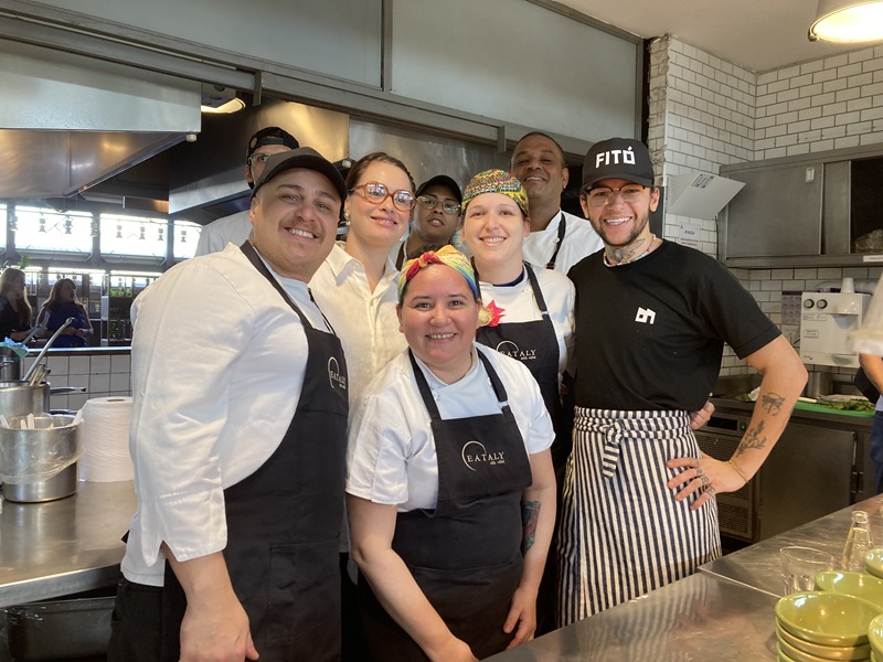 grupo de 7 cozinheiros com aventais do Eataly e do Restaurante Fitó posando para a foto de dentro da cozinha aberta