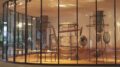 imagem externa do MAM, com paderes de vidro formando uma curva e objetos dentro do museu.