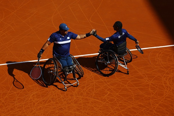 vistos de cima, dois cadeirantes se cumprimentam em uma quadra de saibro em Paris