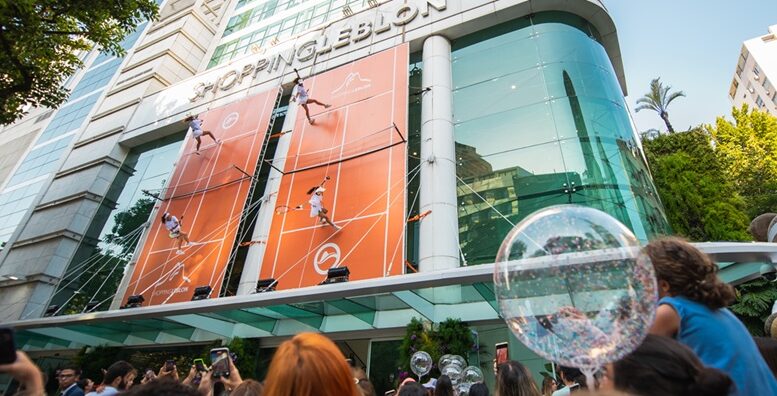 fachada do Shopping Leblon com duas quadras de tenis e bailarinas vestidas de tenistas penduradas simulando um jogo na vertical