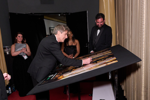 Walter Salles autografa o poster no backstage do Oscar, após receber seu prêmio