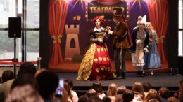 imagem do programa de teatro infantil do ibirapuera, visto do fundo da platéria, com atores no palco e muitas crianças assistindo.