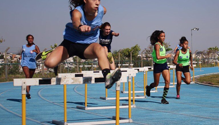 imagem de meninas em uma pista de corrida com barreiras.
