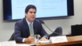 ministro fufuca atrásde uma mesa,falnado ao microfone compater racismo
