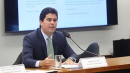 ministro fufuca atrásde uma mesa,falnado ao microfone compater racismo