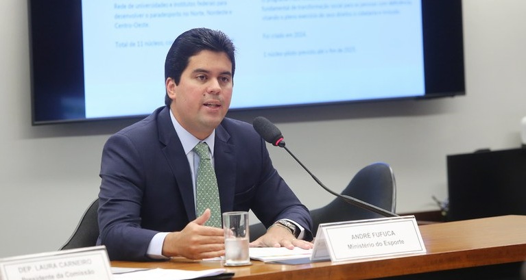 ministro fufuca atrásde uma mesa,falnado ao microfone compater racismo