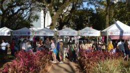 evento com barraquinhas montadas alinhadas atrás de um jardim