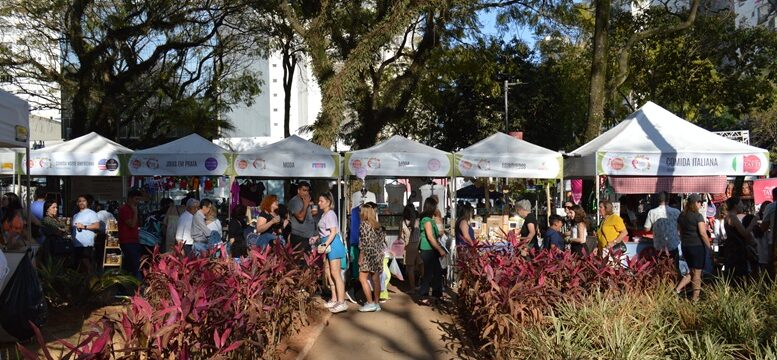 evento com barraquinhas montadas alinhadas atrás de um jardim