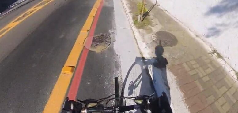 imagem de uma ciclofaixa com a sombra de um ciclista com uma câmera 3D no capacete.