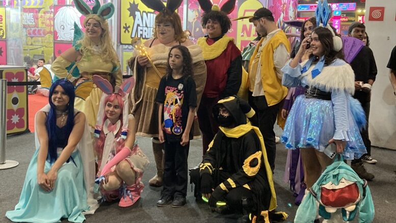 um grupo de pessoas com cosplays posando na entrada do evento