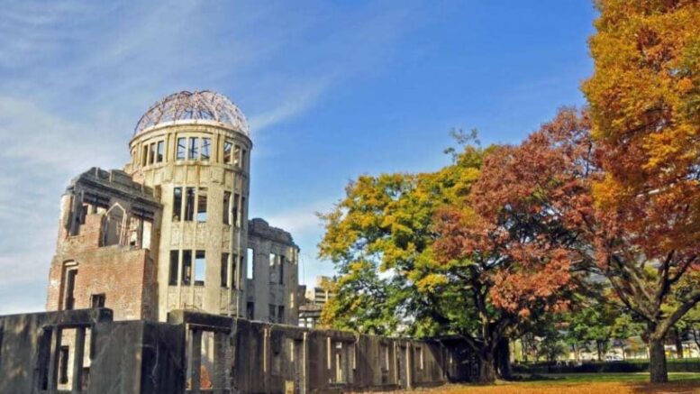 imagem de um pre´dio em ruínas.a lado de árvores com grandes copas e um céu azul