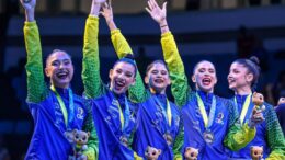 Pódio com equipe brasileira de ginastica ritmica, com a medalha de prata e o mascotinho da competição nas mãos