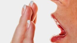 imagem fechada de uma mão em frente a uma boca, vista de lado, como que medindo se tem mau halito.