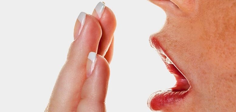 imagem fechada de uma mão em frente a uma boca, vista de lado, como que medindo se tem mau halito.