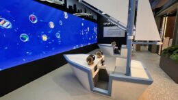 duas estruturas imitando barcos a vela, voltadas para uma parede azul com marcas pintadas