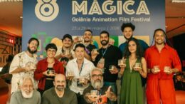 foto com premiados e seus troféus em frente ao banner do festival.