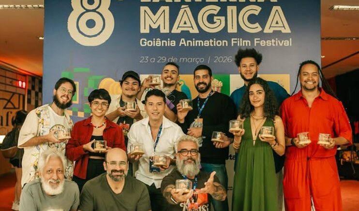 foto com premiados e seus troféus em frente ao banner do festival.