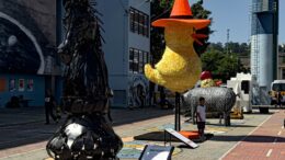 vista oblíqua das cinco esculturas gigantes, expostas a céu aberto no CEU Perus: um cavalo preto, um patinho amarelo com chapeu vermelho e mais longe, um poco, um galo e uma vaca.