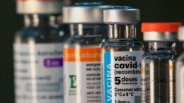 vidros de vacina em primeiro plano um de covid indicando 5 doses