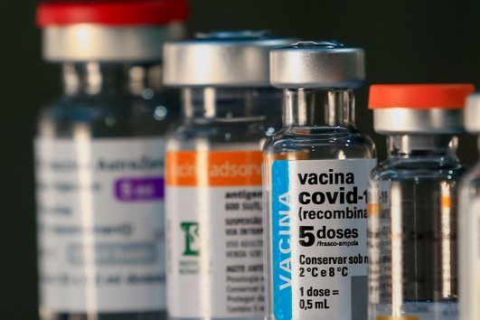 vidros de vacina em primeiro plano um de covid indicando 5 doses
