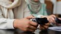 imagem fechada nas mãso de duas jogadoras com controles de games na mão.
