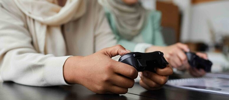 imagem fechada nas mãso de duas jogadoras com controles de games na mão.