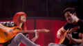 imagem de Mel Lisboa como Rita Lee, tocando violão ao lado do ator Bruno Fraga, como Roberto de Carvalho, também ao violão.