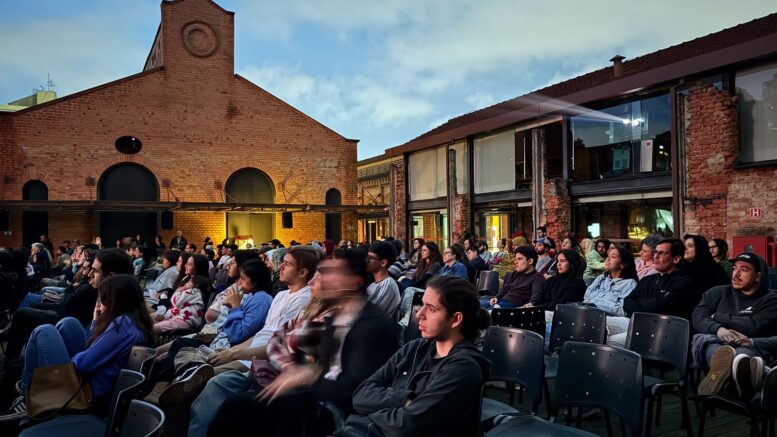imagem da área externa da cinemateca com pessoas em cadeiras, supostamente olhando para uma grande tela de cinema que não aparece na imagem.